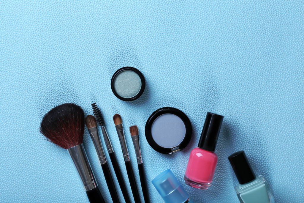 Makeup tools and cosmetics on blue background